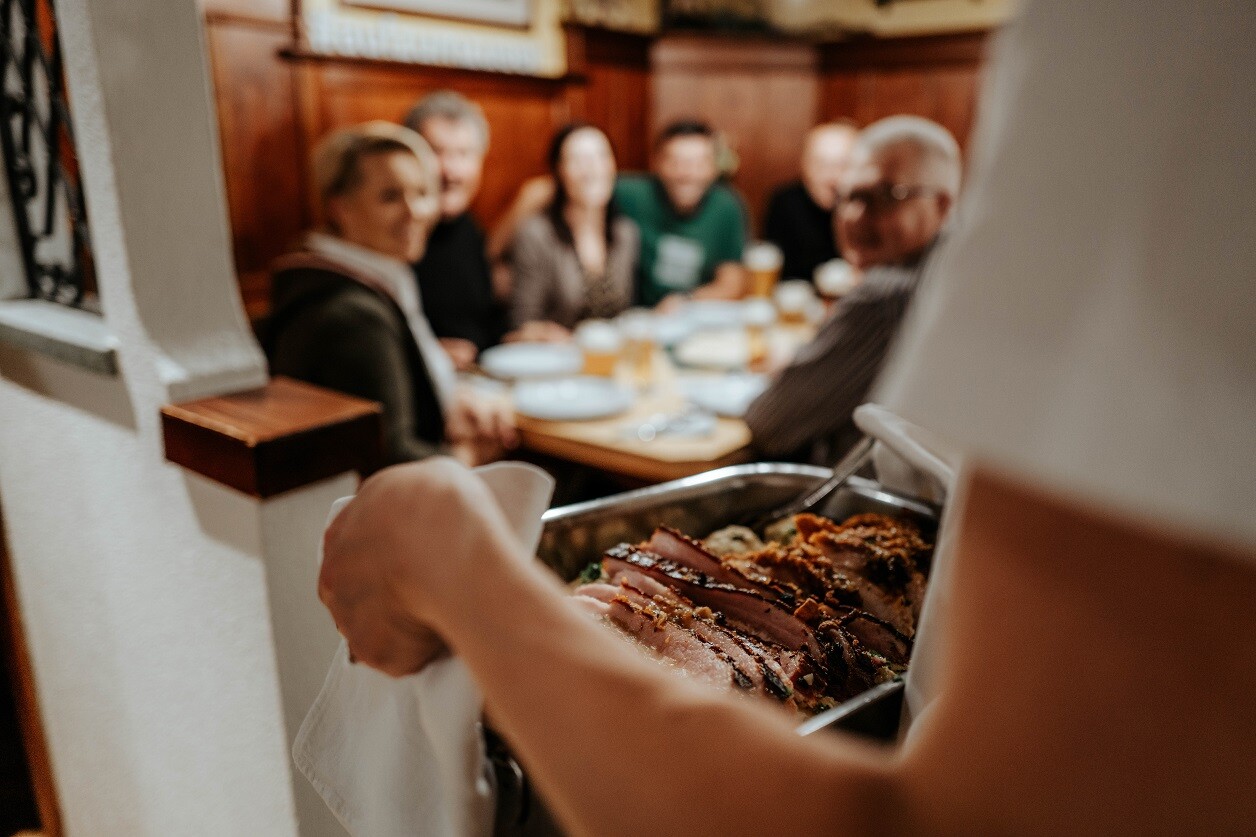 Servicekraft serviert Bratl in der Rein bei einer Weihnachtsfeier im Biergasthof Riedberg in der Bierregion Innviertel
