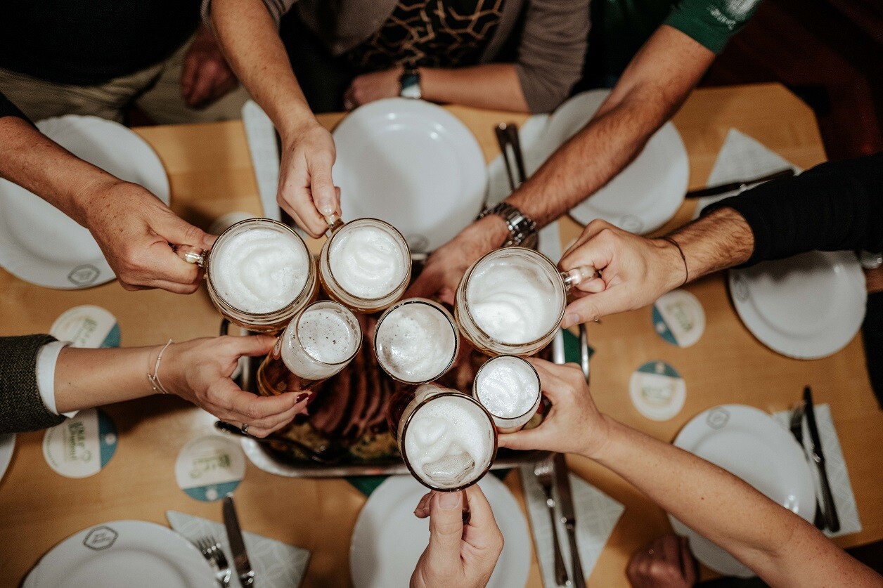 Gruppen stoßen gemeinsam mit Bier über Innviertler Bratl im Biergasthof & Hotel Riedberg an