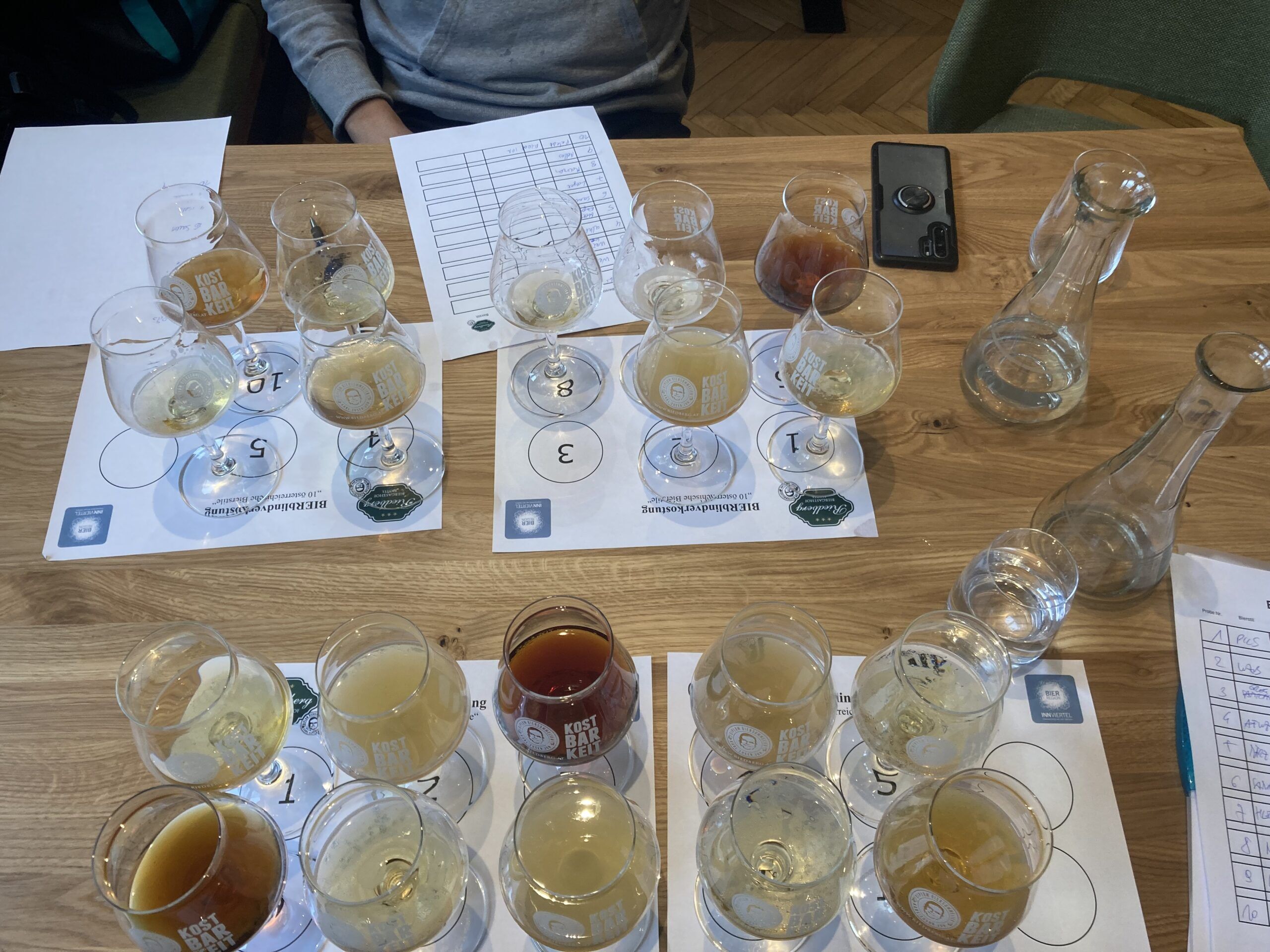 Mehrere nummerierte Verkostungsgläser mit Bierproben und Prüfungsunterlagen auf einem Tisch beim Trainingslager zur Staatsmeisterschaft der Biersommeliers im Biergasthof Riedberg.