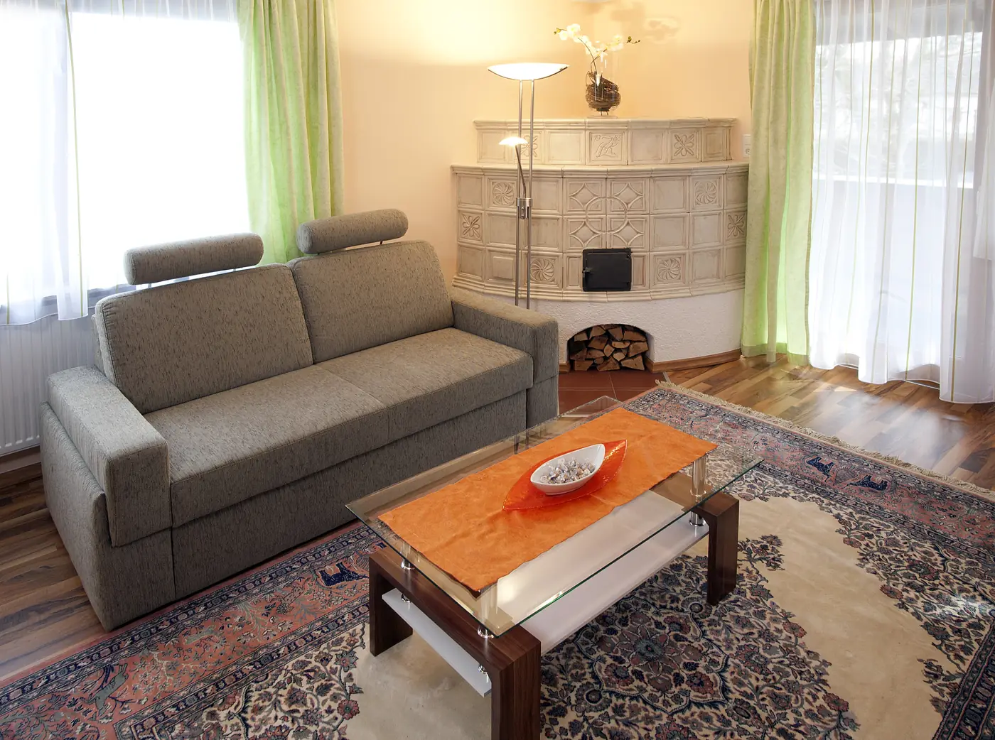 Wohnbereich der Suite 112 mit Sofa und Kachelofen im Biergasthof Riedberg