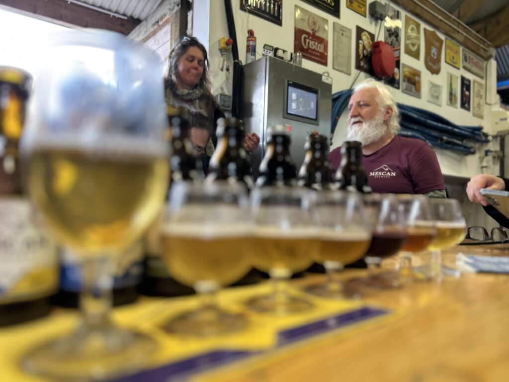 Verkostungsbierreihe der Mescan Brewery im Vordergrund. Im Hintergrund erklärt Brauereigründer Kilian die Biere und die Philosophie seiner Brauerei.