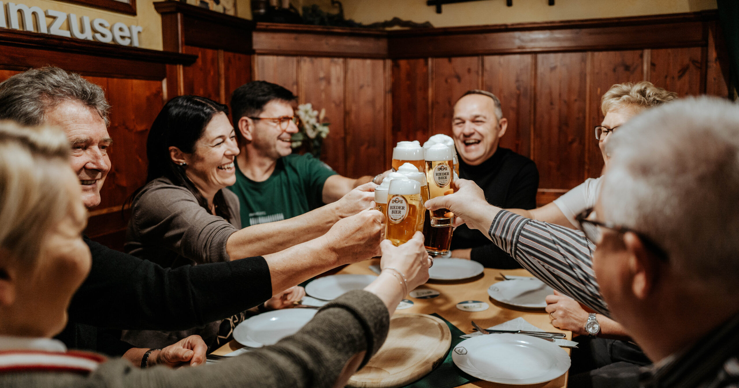 Gäste stoßen im Biergasthof Riedberg im Innviertel gemeinsam mit Bier an.