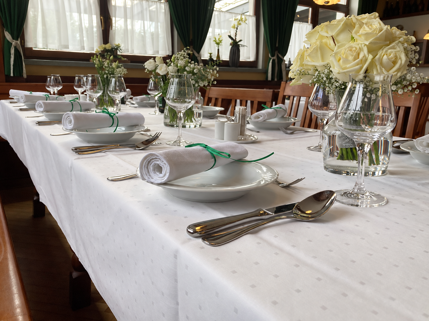 Weiß gedeckter Tisch mit Geschirr, Besteck, Servietten und weißen Blumen im Biergasthof Riedberg