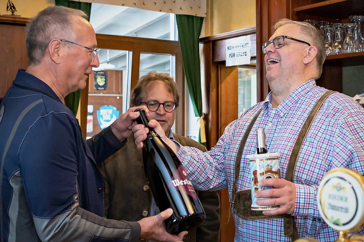 Kollegen überreichen lachend eine große Bierflasche als Geschenk