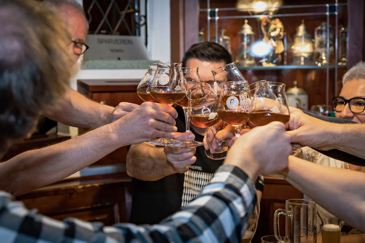 Viele Hände stoßen mit Biergläsern in einer fröhlichen Runde an