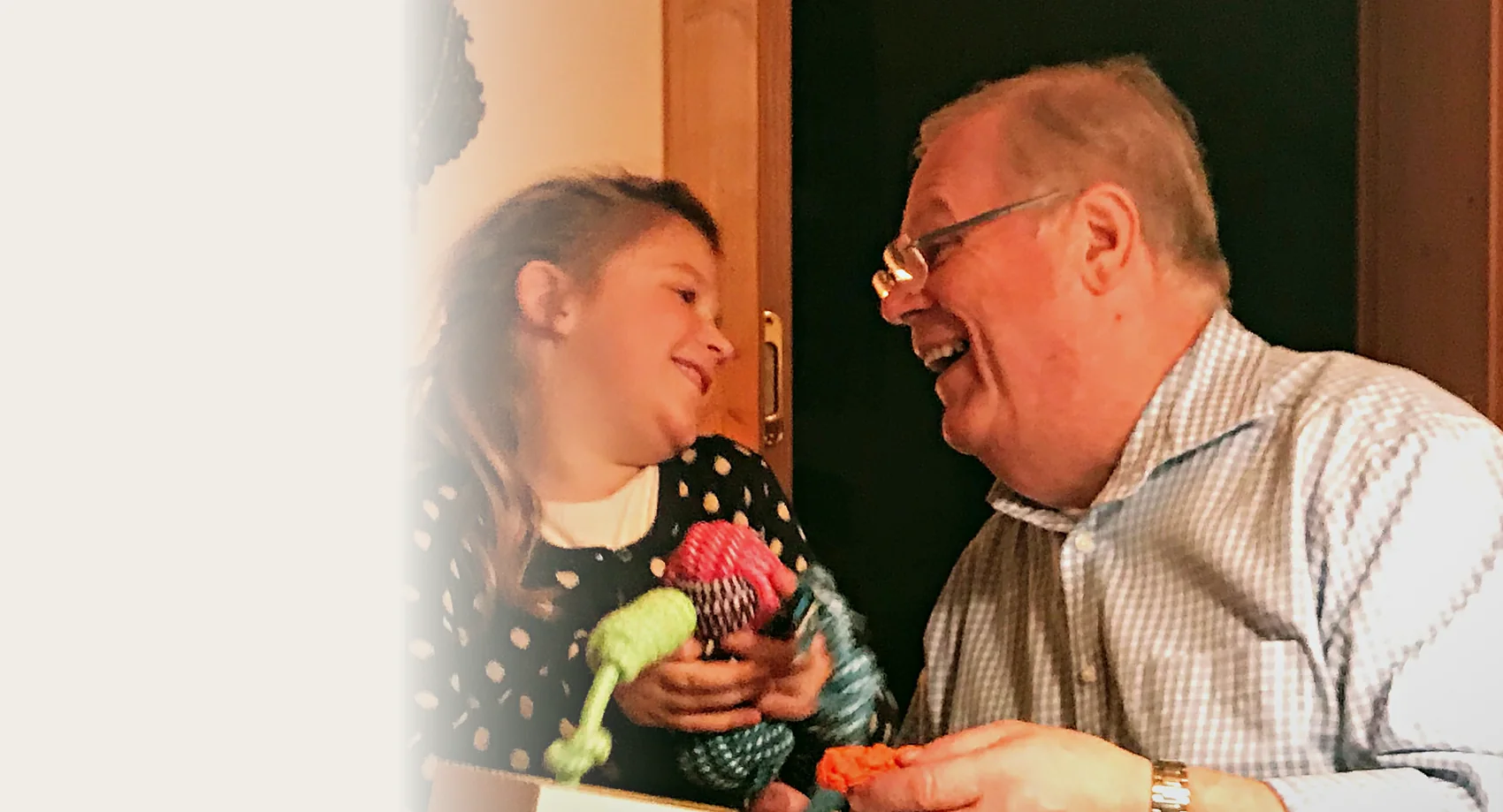Großvater und Enkelin lachen sich beim Auspacken eines Geschenks an
