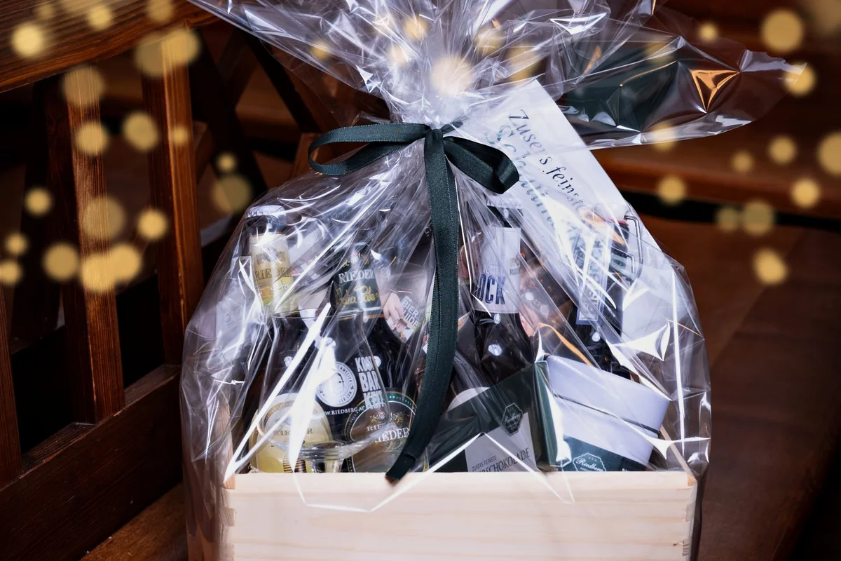 Festlich verpacktes Biergeschenkkisterl mit grüner Schleife und warmem Lichterglanz